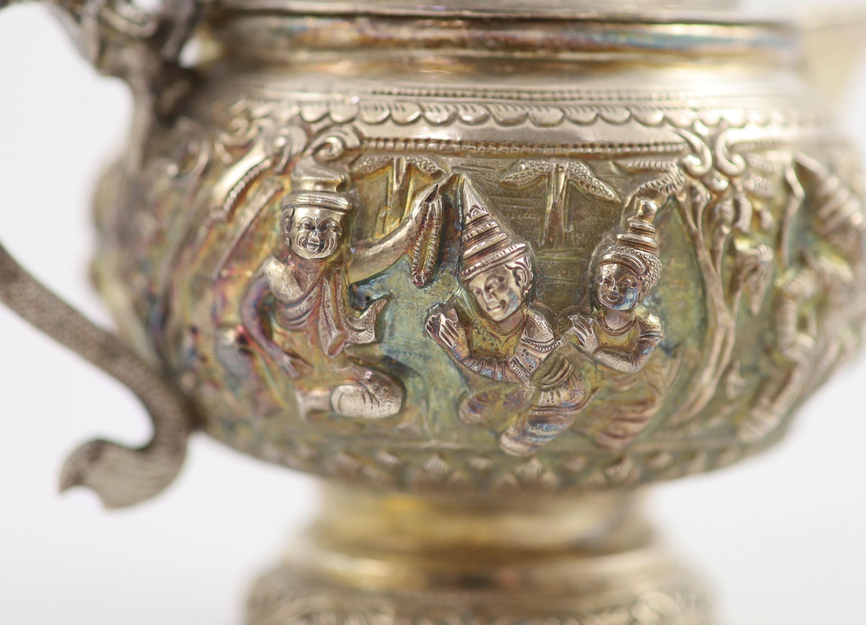 An impressive Burmese Sterling silver (950) three-piece tea service, with tray, cast with figures, teapot with cockerel spout and figural handle